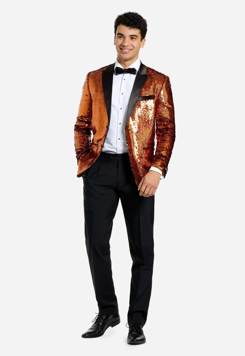 Blazer naranja con lentejuelas y solapas negras, camisa blanca, pajarita negra y pantalones negros. Textura suave, diseño ajustado y acentos brillantes.