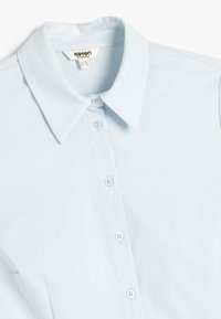 Lichtblauw blouse met kraag en knopen, voorzien van een gladde textuur, subtiele glans en zes bijpassende knopen langs de voorflap.