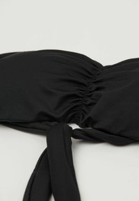 Czarny biustonosz bikini z marszczonym materiałem, z wiązaniem na ramiączkach i gładką teksturą. Odpowiedni do stroju kąpielowego, charakteryzujący się prostym wzornictwem.