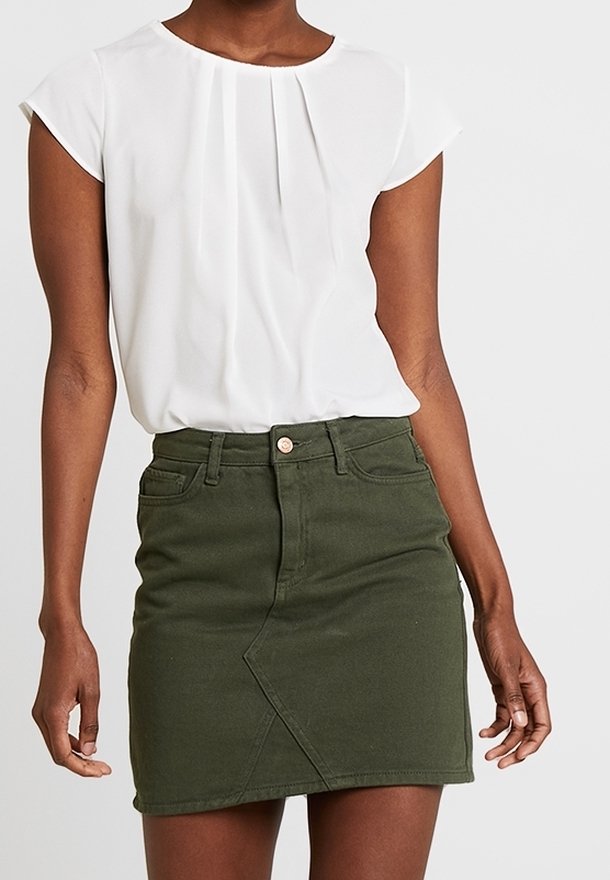 Vit kortärmad blus med veck, tillsammans med en olivgrön jeanskjol som har en diagonalsöm och framknäppning.