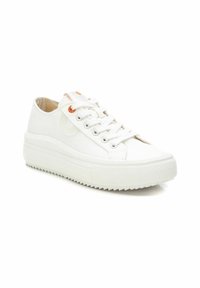 Zapatilla de lona blanca con suela texturizada, puntera redonda y cordones blancos. Presenta un pequeño acento naranja cerca de los ojales.
