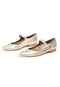 Bailarinas Mary Jane de cuero dorado con punta afilada, tira en el tobillo y un bajo tacón de madera. Acabado texturizado con un forro interior suave.
