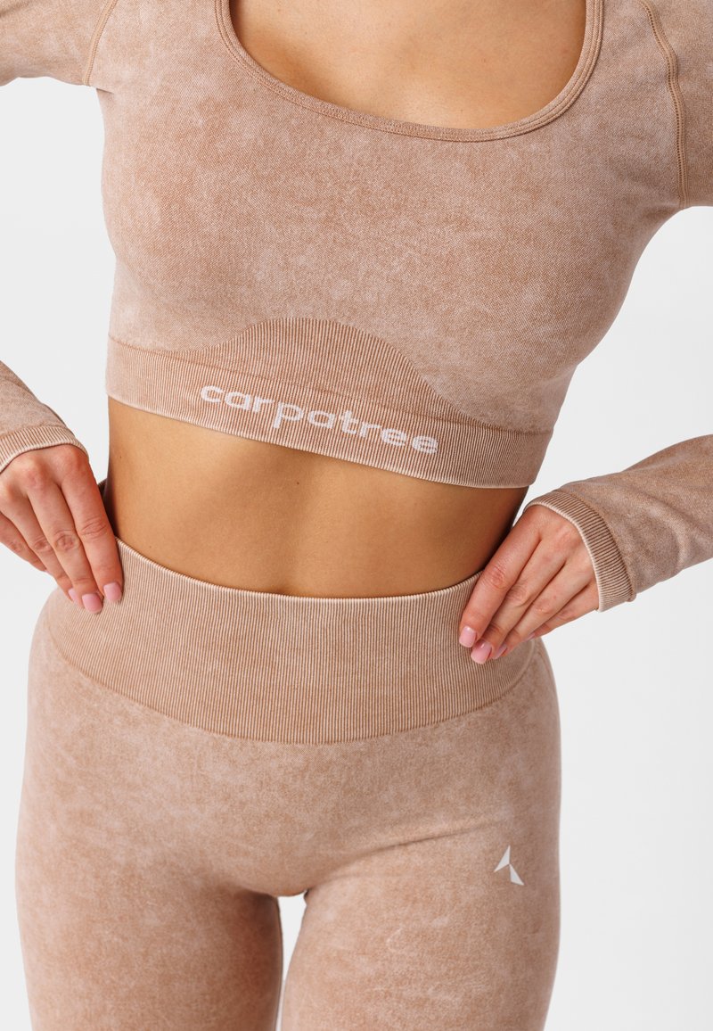 Beżowy zestaw odzieży sportowej składający się z krótkiego topu z prążkowanym pasem oraz dopasowanych legginsów z wysokim stanem o fakturowym wykończeniu z detalem logo.