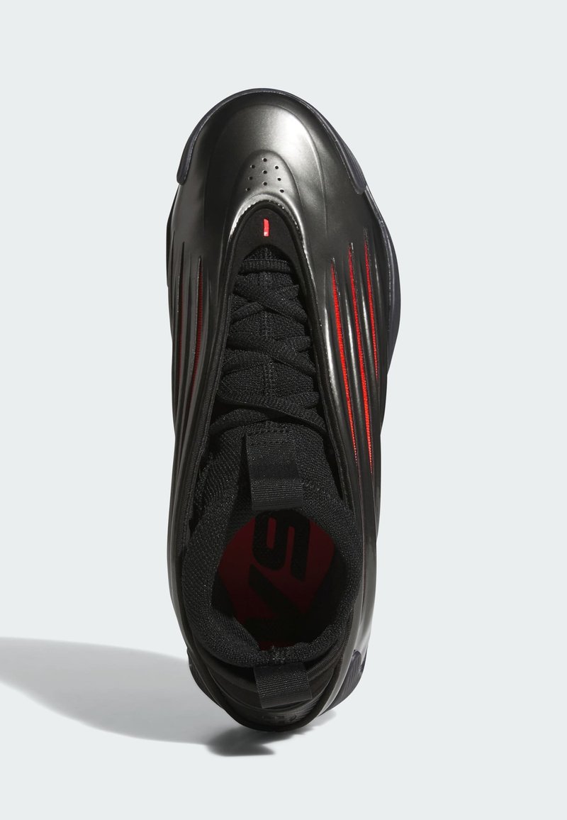 Chaussure de sport noire avec une tige métallique brillante, accents rouges marqués, languette en tissu texturé et silhouette épurée.