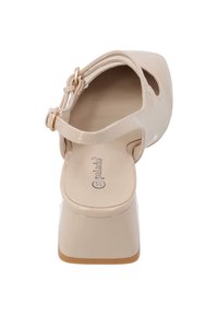 Beige blockklack-sandal med polerad yta, öppen tå och urtagsdesign. Har ett justerbart ankelsnöre med ett guldspänne.