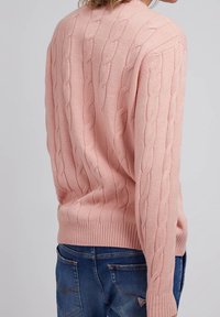 Rosa gestrickter Pullover mit Kabelmuster, gerippten Bündchen und Saum. Passt gut zu blauen Jeans und zeigt ein lässiges und texturiertes Erscheinungsbild.