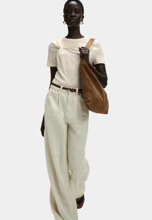 Knit cream t-shirt with twist detail, light beige wide-leg pants, and a brown suede shoulder bag. Smooth textures and relaxed fit.