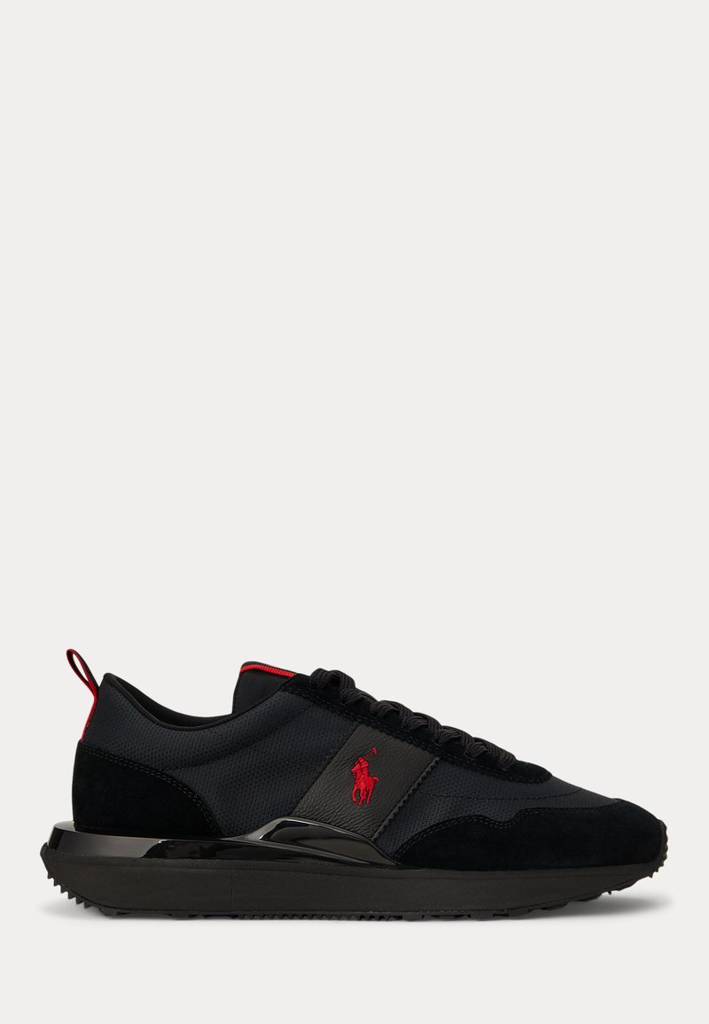 Zwarte lage sneaker met rood logo en accenten, vetersluiting en een dikke rubberen zool met gestructureerde grip.