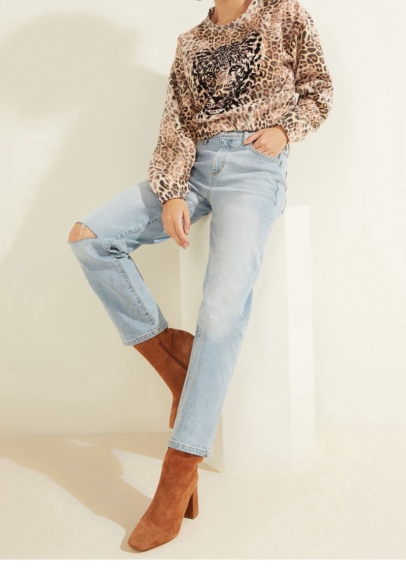 Sudadera de estampado de leopardo con detalles en negro, jeans desgastados de color azul claro y botas de ante marrón hasta el tobillo con puntera cuadrada y tacón ancho.