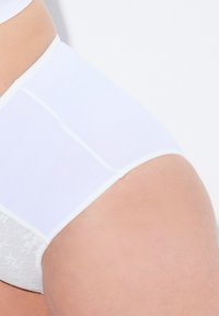 Culotte taille haute blanche en tissu lisse. Présente un panneau en dentelle sur le côté. Texture douce avec des coutures nettes et un design simple.