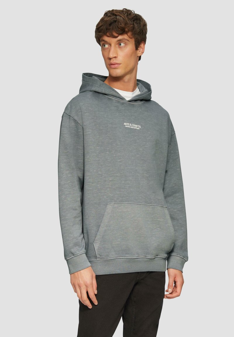 Sudadera gris hecha de tela suave, con un bolsillo frontal, capucha con cordón y logotipo blanco en el pecho. Diseño sencillo y ajuste casual.