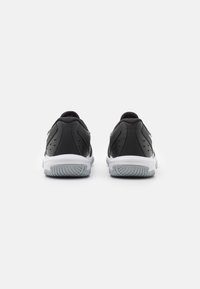 Des chaussures de sport noires avec une tige en cuir lisse et une semelle en caoutchouc blanche, présentant des accents texturés et une perforation minimale pour la respirabilité.