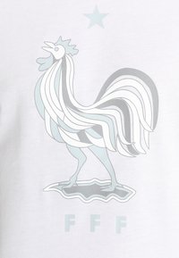 Tyylitelty kukko seisoo abstraktilla muotolla, jonka yläpuolella on tähti ja alapuolella vaaleanharmailla ja valkoisilla sävyillä kirjaimet "FFF".