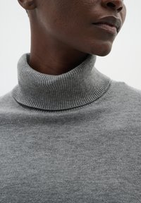 Gray turtleneck sweater made of soft knit material, featuring a ribbed collar and smooth texture, without any visible patterns or accents.