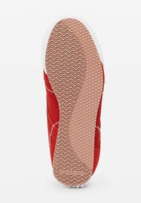 Rote Sneaker mit einer strukturierten Oberfläche, weißen Nähten und einer Gummisohle mit einem wellenförmigen Muster sowie "Desigual"-Markenaufdruck.