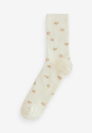 Knee-length socks in cream with a ribbed texture and small brown flower patterns throughout. Soft fabric, seamless toe design.