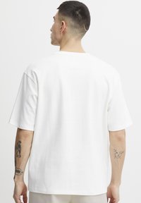 White cotton t-shirt, relaxed fit, short sleeves, crew neck. Smooth texture with no visible patterns or hardware details.