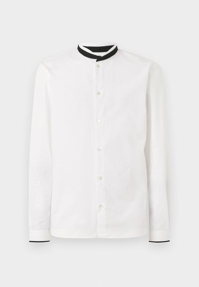 Hvit langermet skjorte med svart mandarin-krage, med knappelukking foran og kontrasterende mansjetter med en subtil tekstur.