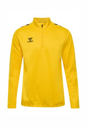 Żółty sweter z długimi rękawami i kołnierzem na ćwierć zamka. Posiada czarne akcenty oraz logo na piersi. Gładki, lekki materiał.