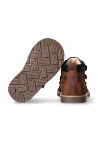 Stivale in pelle marrone con accenti neri, punta rotonda, tre fibbie e suola in gomma texturizzata con un motivo geometrico.