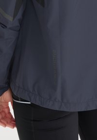 Navy lichte jas met een gladde, matte textuur, voorzien van 'ENDURANCE' branding en contrasterende grijze accenten op de schouders.