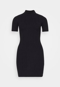 Abito nero lavorato a maglia con collo alto, maniche corte e vestibilità aderente. Presenta un motivo a zig zag testurizzato su tutta la superficie.