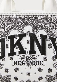 Baltas audinio maišas su juodais paisley raštais, drąsiais "DKNY" rašmenimis ir siuvinėjimu "NEW YORK". Minkšta tekstūra su struktūrizuota forma.