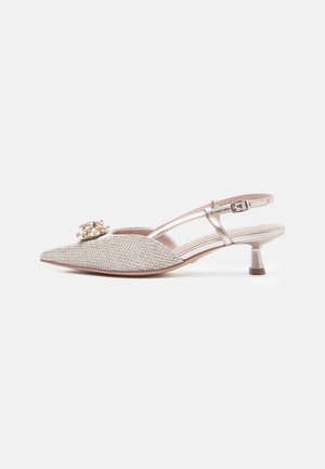 Dei tacchi slingback beige con punta affilata, impreziositi da una spilla a forma di perla, tomaia dalla texture interessante e un sottile tacco di media altezza.