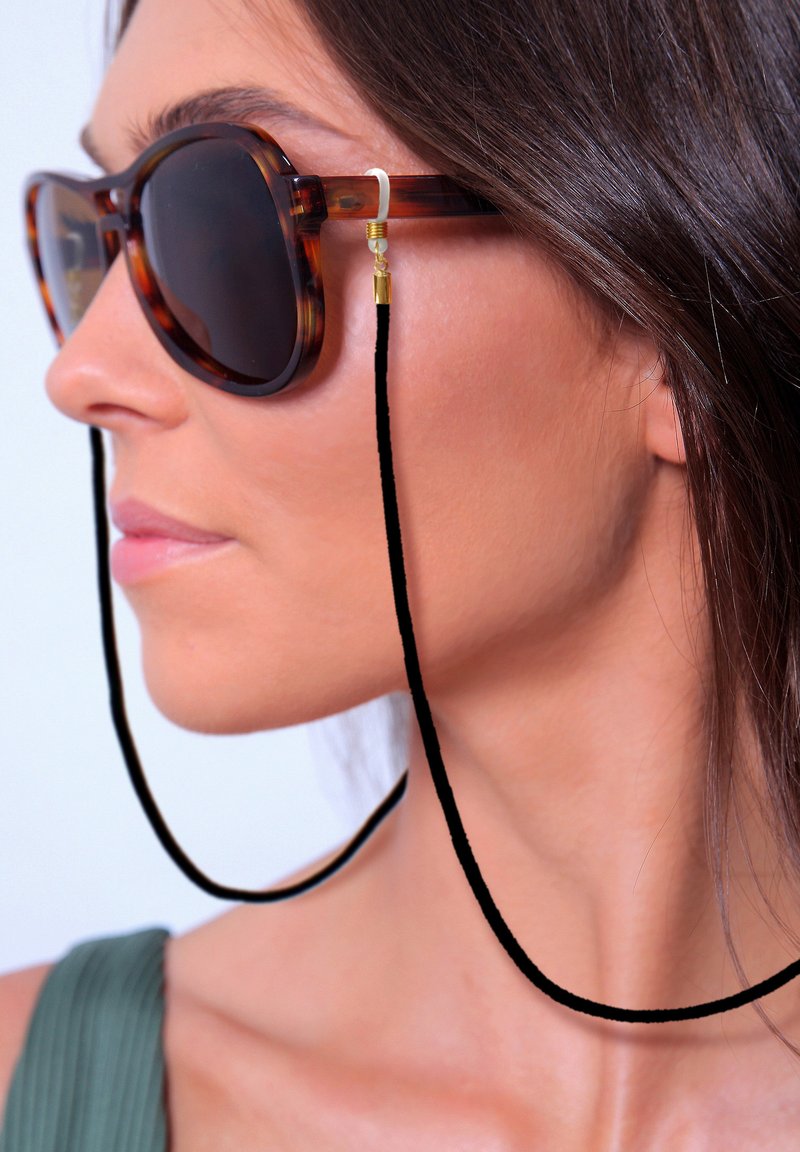 Schildpatt-Sonnenbrille mit dunklen Gläsern, ausgestattet mit einem schwarzen Cord und goldfarbenen Beschlägen zur Sicherung. Die Form ist rund mit einer polierten Oberfläche.