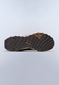 Trail sko outsole med en tekstureret sort gummioverflade og fremtrædende lugs for trækkraft, akkompagneret af en tan midsole og en brun detalje.
