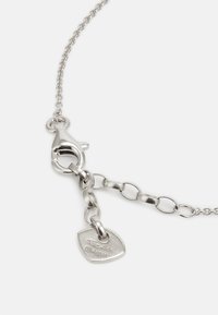 Silberne Kettenhalskette mit einem Karabinerverschluss, ovalen Gliedern und einem flachen Anhänger mit gravierten Markierungen. Glatte Textur und polierte Oberfläche.