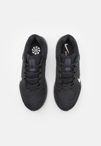 Baskets de sport noires avec une tige en maille, lacets ronds, talons renforcés et un swoosh blanc de Nike. Semelle intérieure à motifs avec détail du logo.