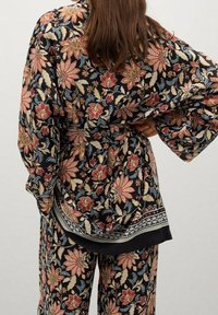 Kimono župan s květinovým potiskem, širokými rukávy, černým pozadím a oranžovými a krémovými květinami, s vzorovaným lemem. Měkká, lehká tkanina.