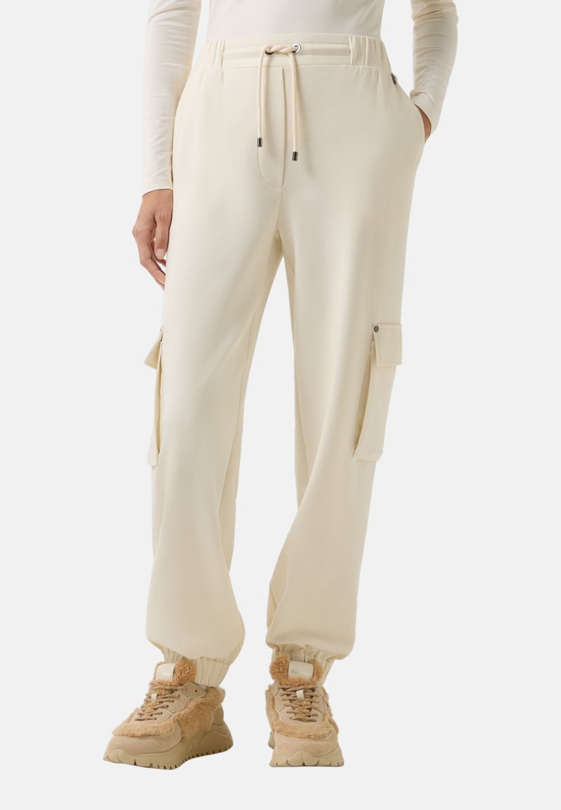 Crème joggings met zijvakjes, elastische enkels en een verstelbare trekkoord tailleband. Gecombineerd met beige chunky sneakers.