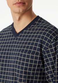 Navy V-neck shirt with white grid pattern, short sleeves, and a left chest pocket. Made from soft cotton with a smooth texture.