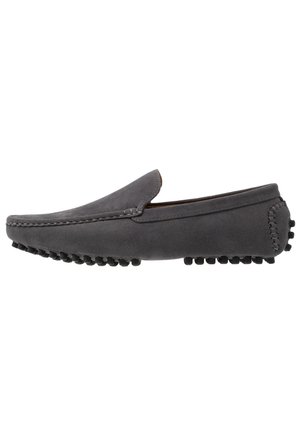 Mocassin homme en daim gris avec des picots en caoutchouc sur la semelle et le talon, style slip-on, coutures détaillées le long des bords, vue latérale sur fond blanc.
