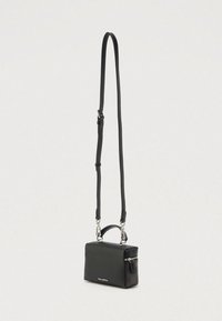 Melna ādas plecu soma ar gludu tekstūru, taisnstūrveida formu, noņemamu siksnu un mazu priekšējo rāvējslēdzēja kabatu. Sudraba krāsas metāla akcenti.