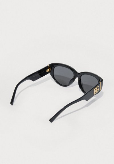 Óculos de sol pretos com acabamento brilhante, forma de gato, lentes tonalizadas e detalhe do logótipo dourado na lateral. Design elegante com hastes finas.