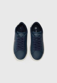 Marineblå sneakers med overdel i syntetisk læder, hvid gummisål og marineblå snørebånd. Har "Tommy Hilfiger" brandmærke på tungen.