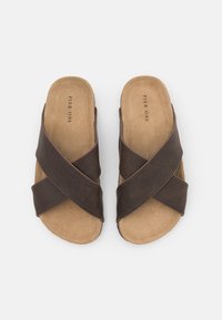 Sandale maro cu curele încrucișate, încălțate cu un material din piele texturată, talpă căptușită și talpă plată. Logo-ul mărcii imprimat pe interior.