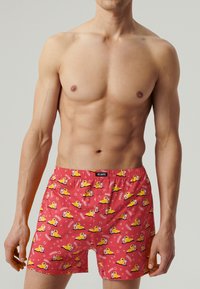 Czerwone bokserki z wzorem gumowych kaczek i bąbelków, wykonane z lekkiego materiału, z elastycznym pasem ze znakiem towarowym.