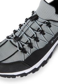 Scarpa da ginnastica grigia con tomaia in rete, dettagli in gomma nera e sistema di lacci rapidi. Superficie testurizzata e suola robusta per una buona aderenza.