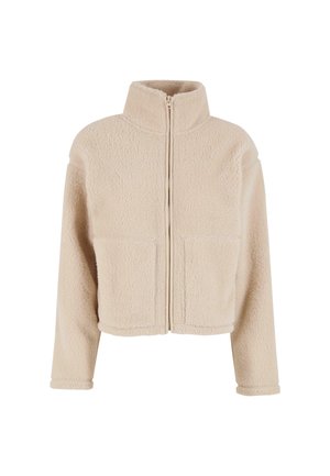 Beige Fleecejacke mit hohem Kragen, Reißverschluss vorne und zwei aufgesetzten Taschen. Sie hat einen cropped Schnitt und eine weiche Textur.