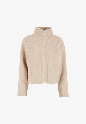 Beige fleece-takki korkealla kauluksella, etuvetoketjulla ja kahdella läpätaskulla. Ominaisuuksiin kuuluu lyhennetty malli ja pehmeä tekstuuri.