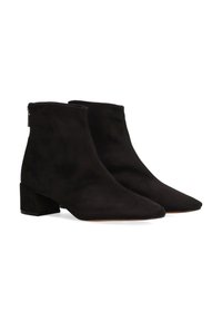 Botines de ante negro con punta afilada y tacón grueso. Presentan un cierre de cremallera en la parte posterior para facilitar su uso. Textura suave.