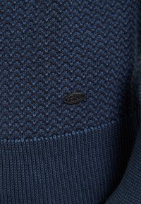 Maglione lavorato a maglia blu navy con motivo a zigzag, tessuto a costine nella parte inferiore e un piccolo patch logo nero.