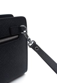 Borsa a tracolla nera con texture, dotata di chiusura con zip argentata, caratterizzata da una tracolla removibile e una forma rettangolare, che mette in risalto un design elegante.