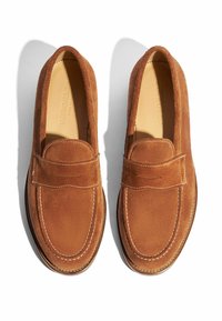 Bruine suède loafers met een afgeronde neus, gestikte details en een zachte textuur. Instapontwerp met een subtiele frontaccent.