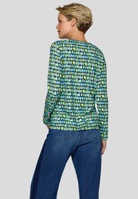 Langarmshirt mit geometrischem Muster aus blauen und grünen Formen auf navy Hintergrund. Weicher Stoff mit lockerer Passform.