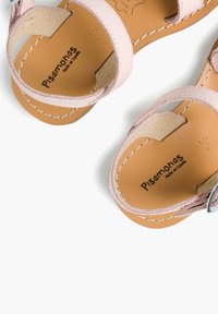 Lichtroze leren sandalen met twee banden, een gesp en een tanleren binnenzool. Voorzien van zichtbare stiksels en het merklogo aan de binnenkant.